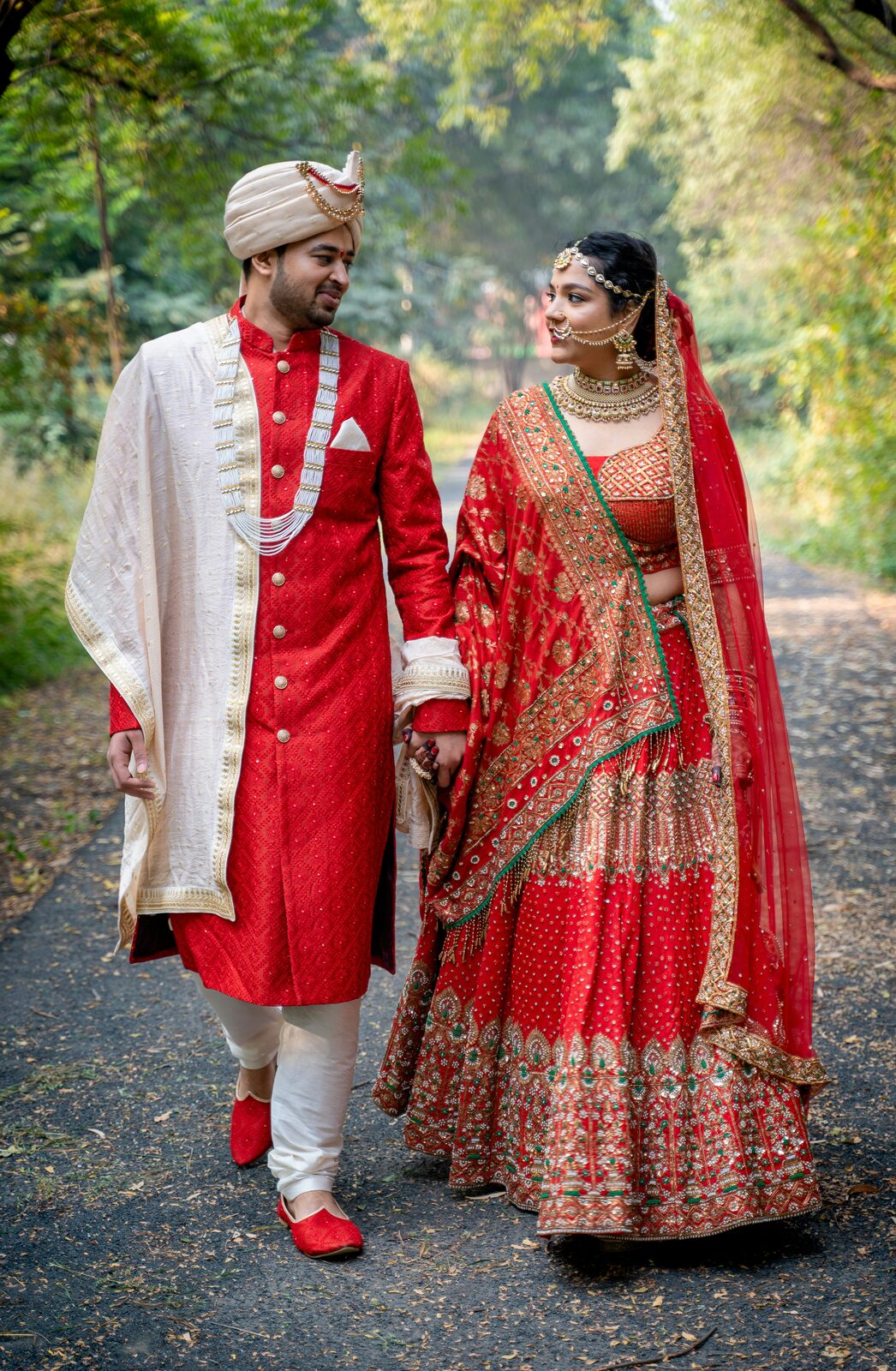 A couple in traditional red wedding attire walking hand in hand